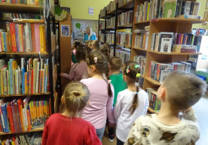Dzieci przechodzą pomiędzy regałami z książkami.